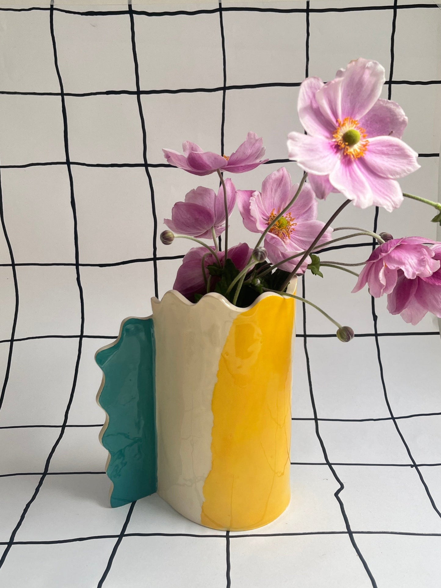 Colorful vase with flowers against a black and white grid background