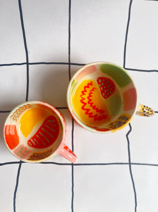 View from above of two espresso sized cups decorated with colourful patterns. 
