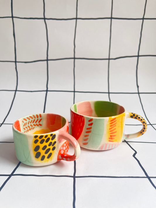 Two espresso sized cups decorated with colourful patterns. 